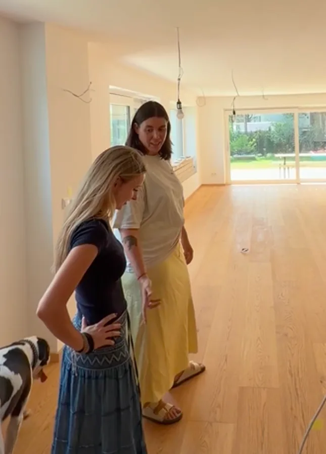 Two colleagues and the studio dog in a stripped-back apartment with pendant cables still hanging