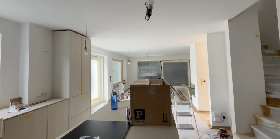 Kitchen mid-renovation with cabinets fitted and lamps still hanging bare