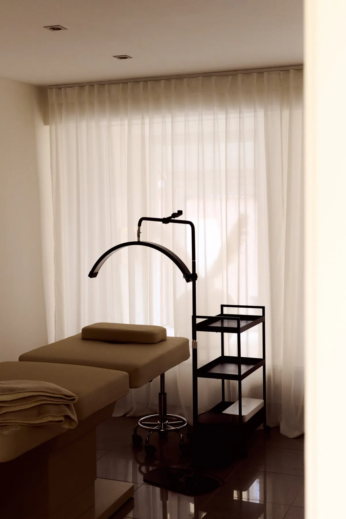 Cosmetics Studio Munich: treatment couch and trolley against a full-height sheer curtain