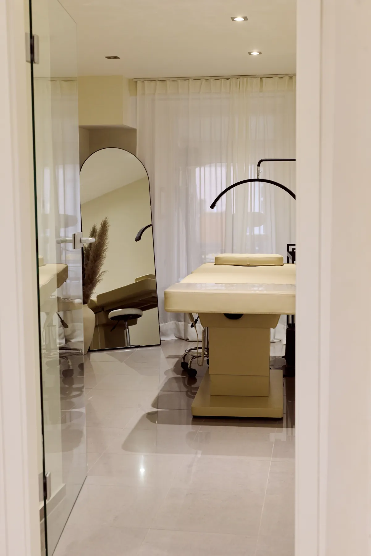 Cosmetics Studio Munich: treatment room with an arched mirror, sheer curtains and a half-moon lamp