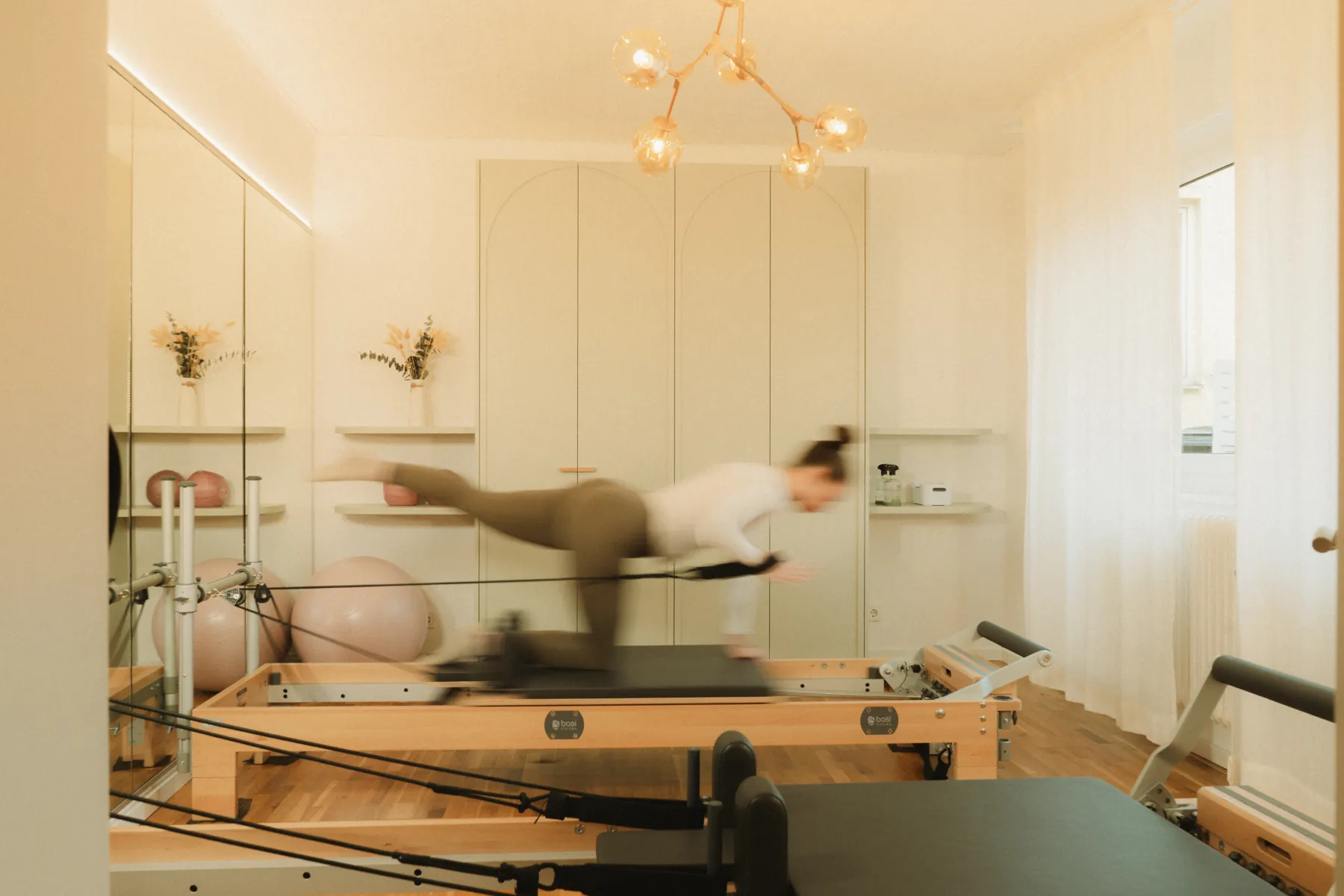 Pilates Studio Munich: training on a reformer in front of the mirrored wall of the atelier