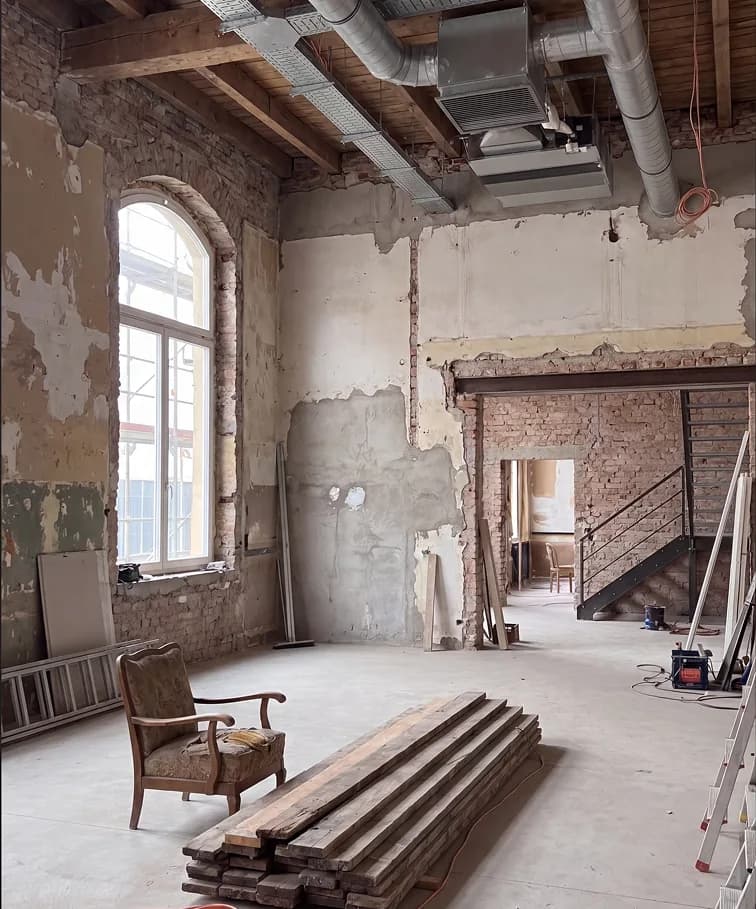 Gutted loft with exposed brick, an arched window and stripped plaster before the assessment
