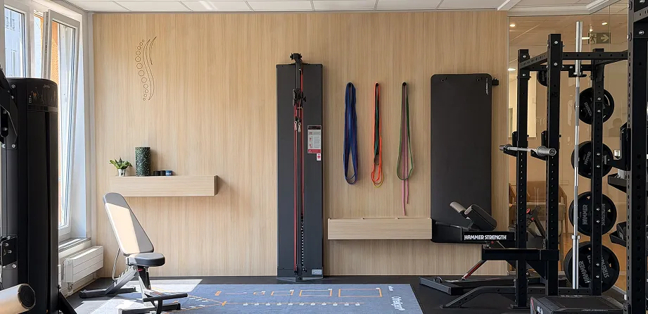 Training room of the Munich physiotherapy practice with oak-slatted walls and a wall-mounted rack