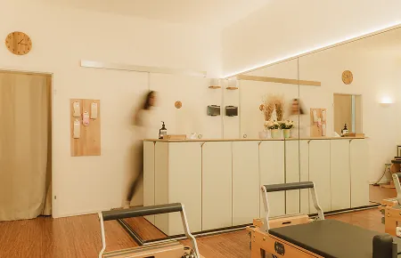 Training room of the Munich Pilates studio with pale custom cabinetry, mirrors and reformers