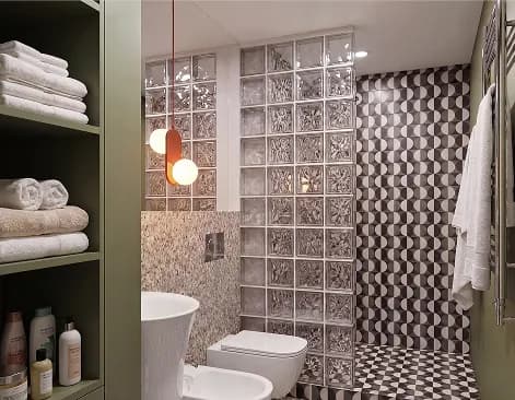 Bathroom of the Milan loft with a glass-brick shower wall, olive shelving and graphic tiles